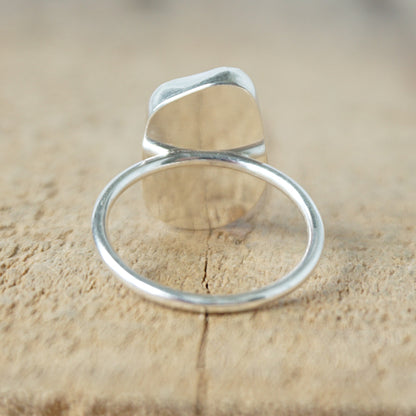 back view of a silver ring with cobalt blue sea glass, on a wooden surface.