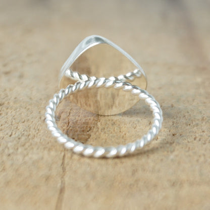back view of a silver ring with dark green sea glass, on a wooden surface.