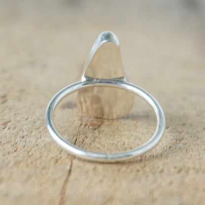 back view of a silver ring with kelly green sea glass, on a wooden surface.
