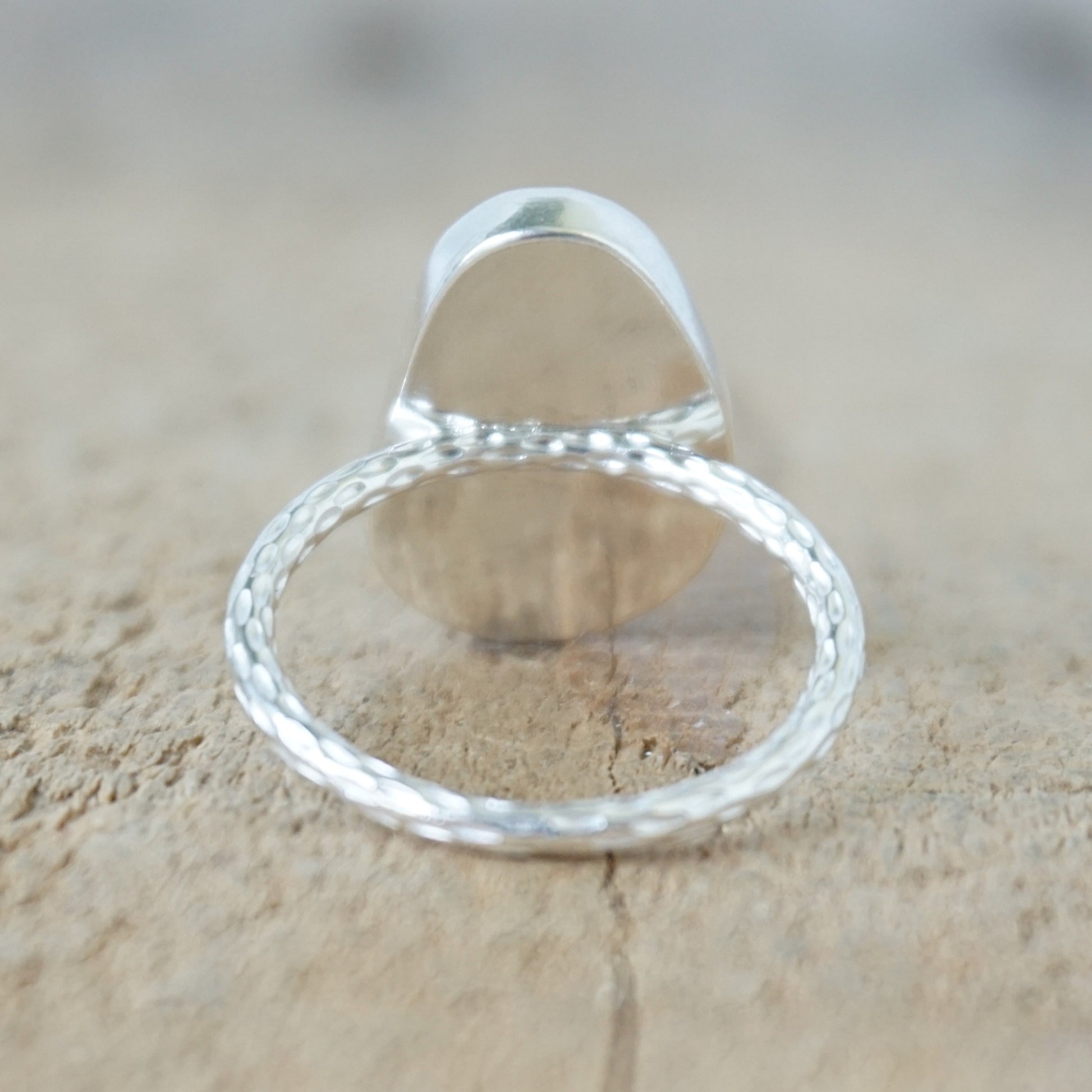 back view of a silver ring with kelly green sea glass, on a wooden surface.