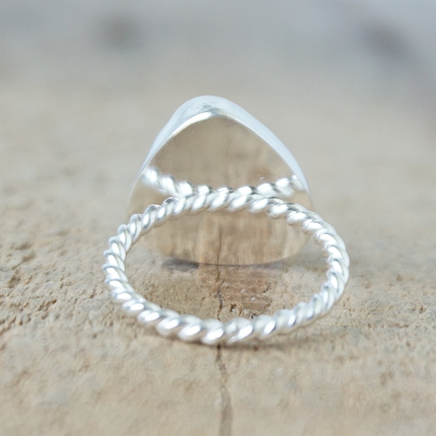 back view of a silver ring with kelly green sea glass, on a wooden surface.