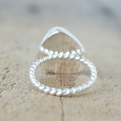 back view of a silver ring with kelly green sea glass, on a wooden surface.