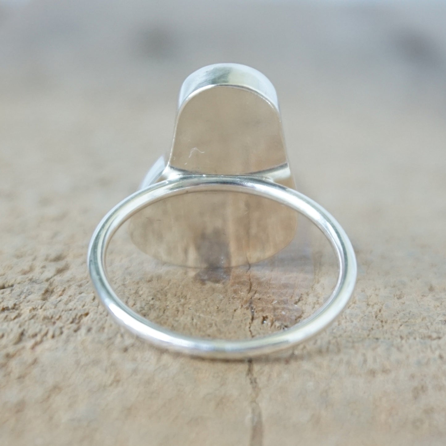back view of a silver ring with seafoam green sea glass, on a wooden surface.