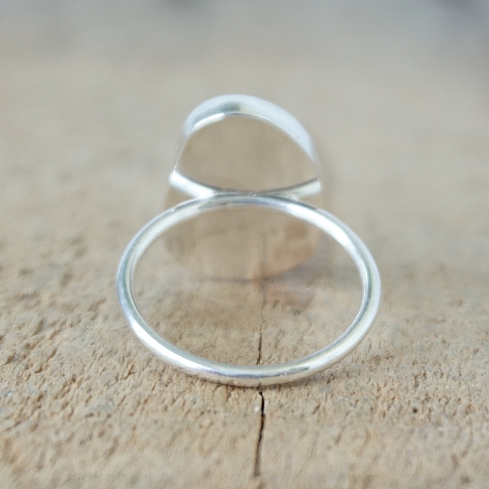 back view of a silver ring with seafoam green sea glass, on a wooden surface.