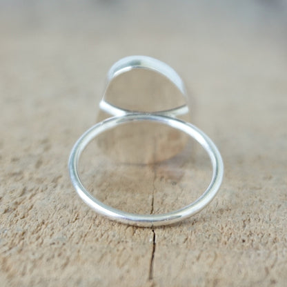 back view of a silver ring with seafoam green sea glass, on a wooden surface.