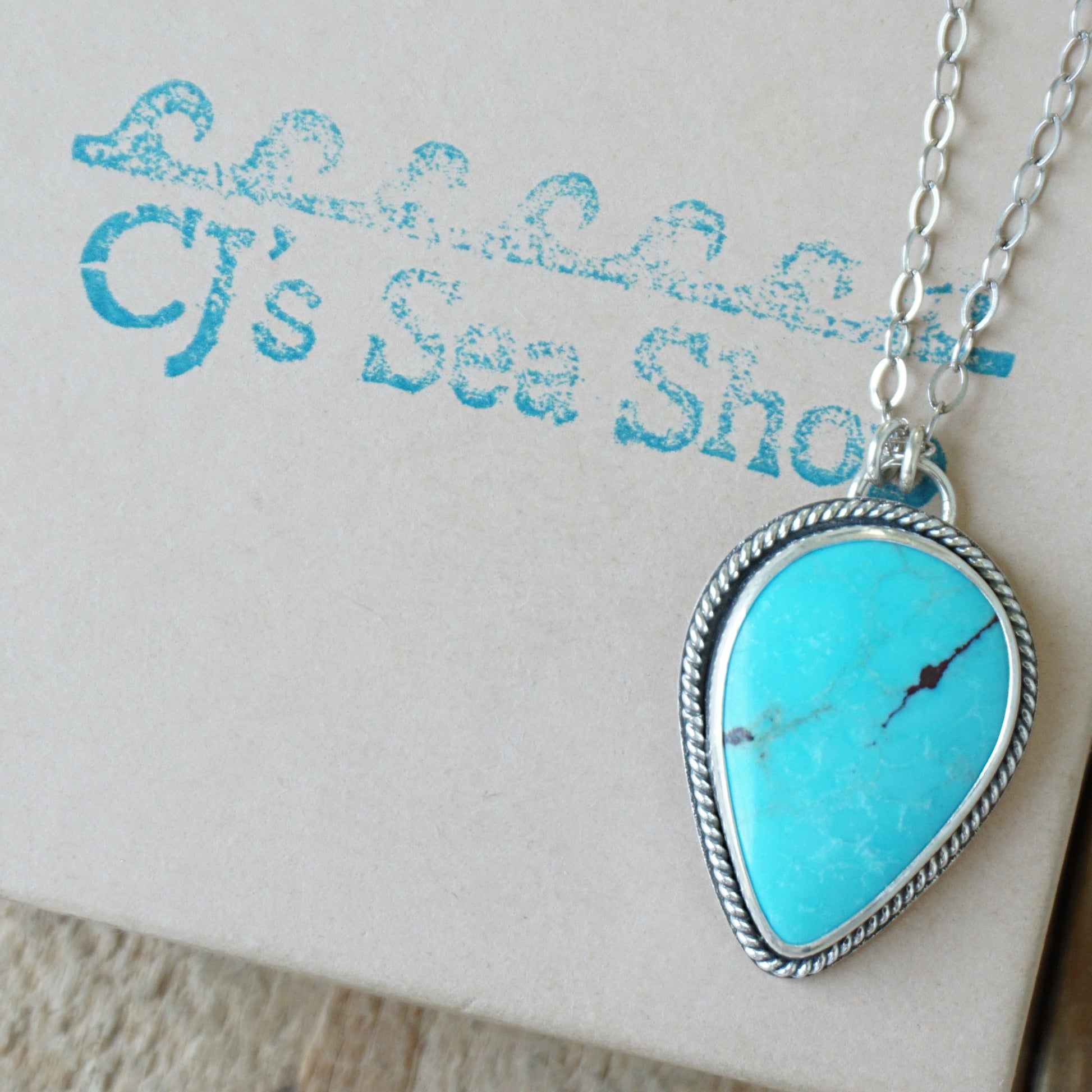 Sterling silver pendant with teardrop shaped turquoise stone, displayed on a gift box