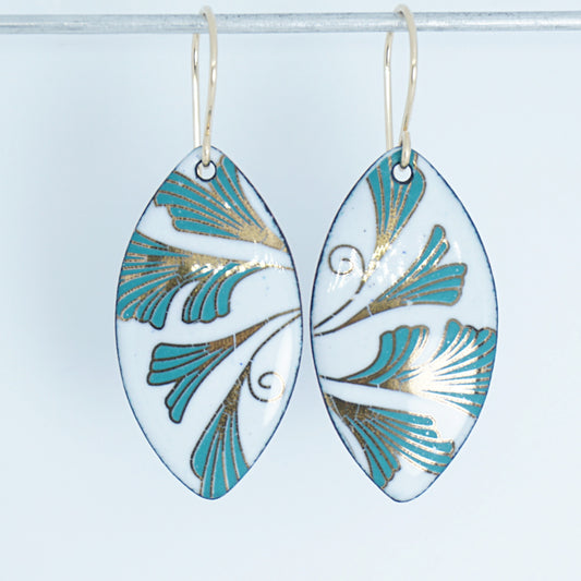 Marquis shaped enamel earrings with green and gold leaves, against a white background
