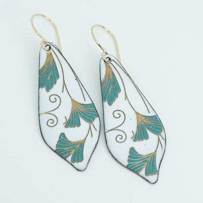 Teardrop shaped enamel earrings with green and gold leaves, against a white background