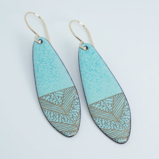 a pair of seafoam green enamel earrings with gold designs, against a white background