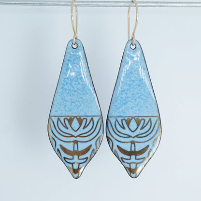 a pair of light blue enamel earrings with gold designs, against a white background