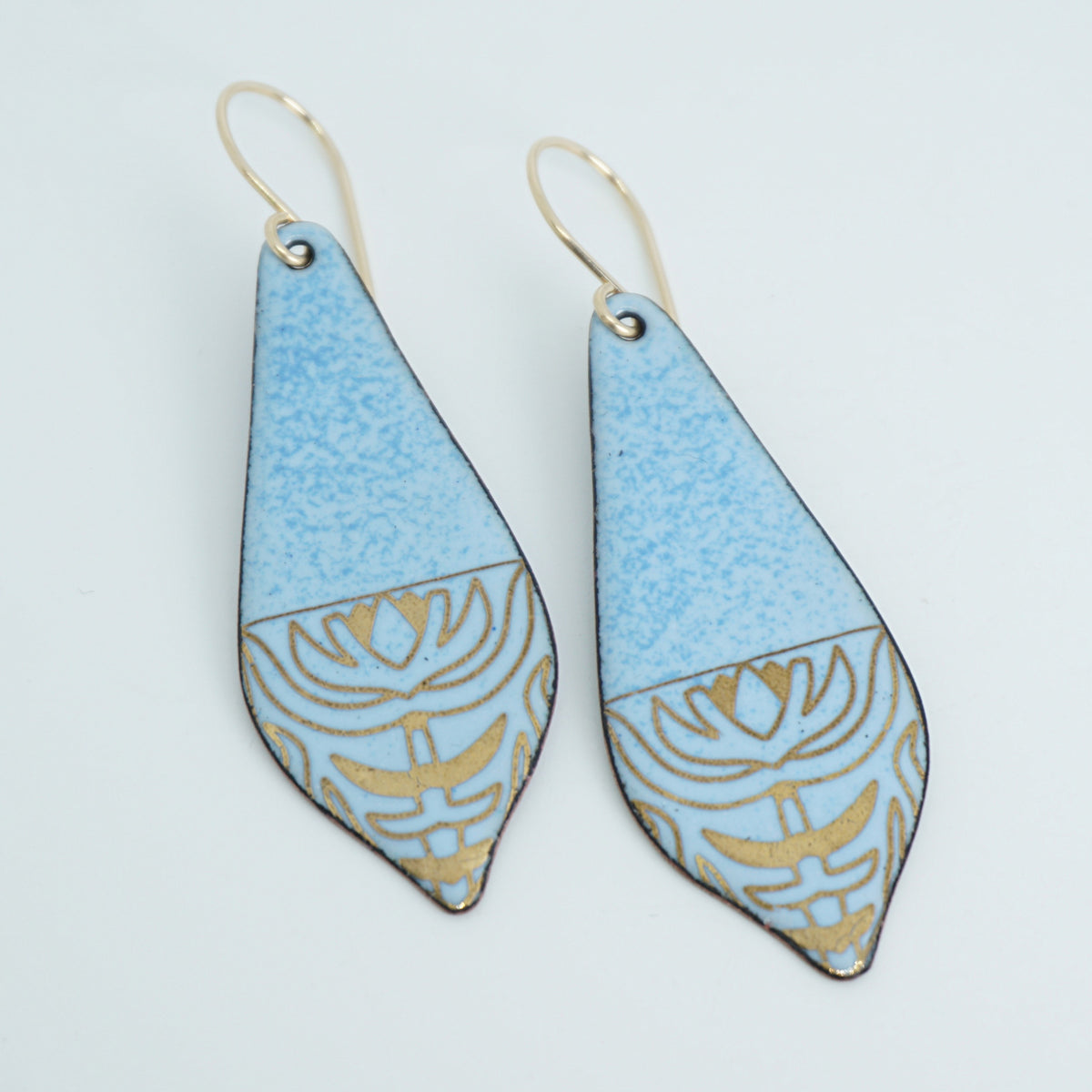a pair of light blue enamel earrings with gold designs, against a white background