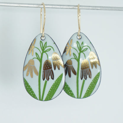 a pair of seafoam green enamel teardrop shaped earrings with gold flower accents, against a white background