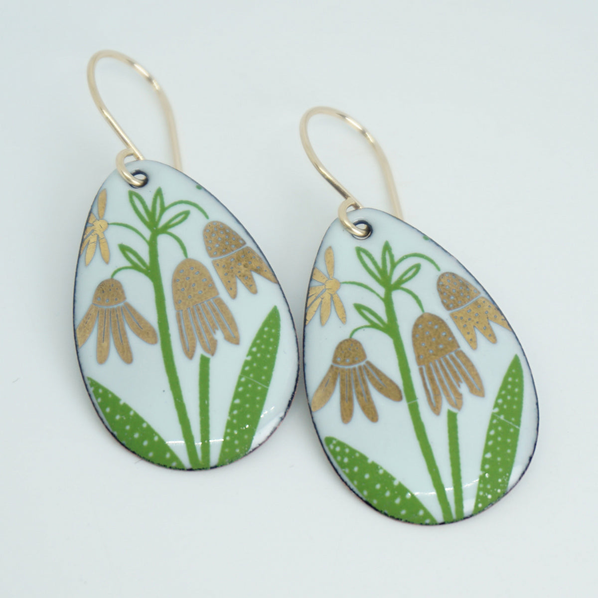a pair of seafoam green enamel teardrop shaped earrings with gold flower accents, against a white background