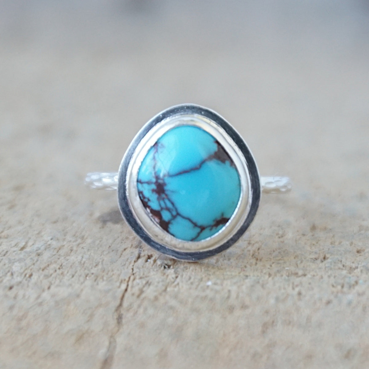 silver ring with a turquoise ring, against a wooden background
