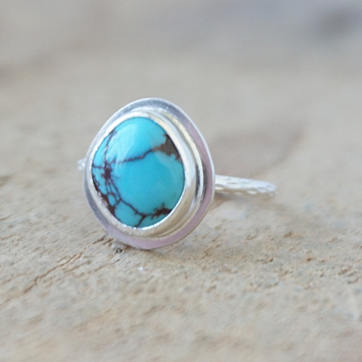 silver ring with a turquoise ring, against a wooden background