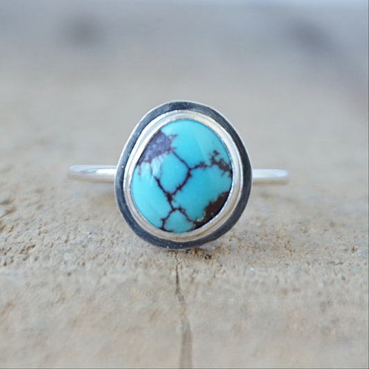 silver ring with a turquoise stone, against a wooden background