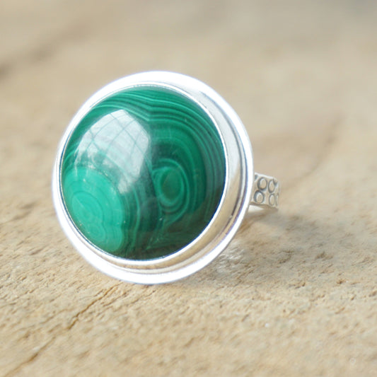 silver ring with a green stone on a wooden background