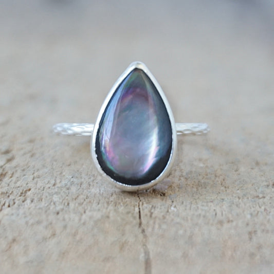 silver ring with a dark grey stone, against a wooden background