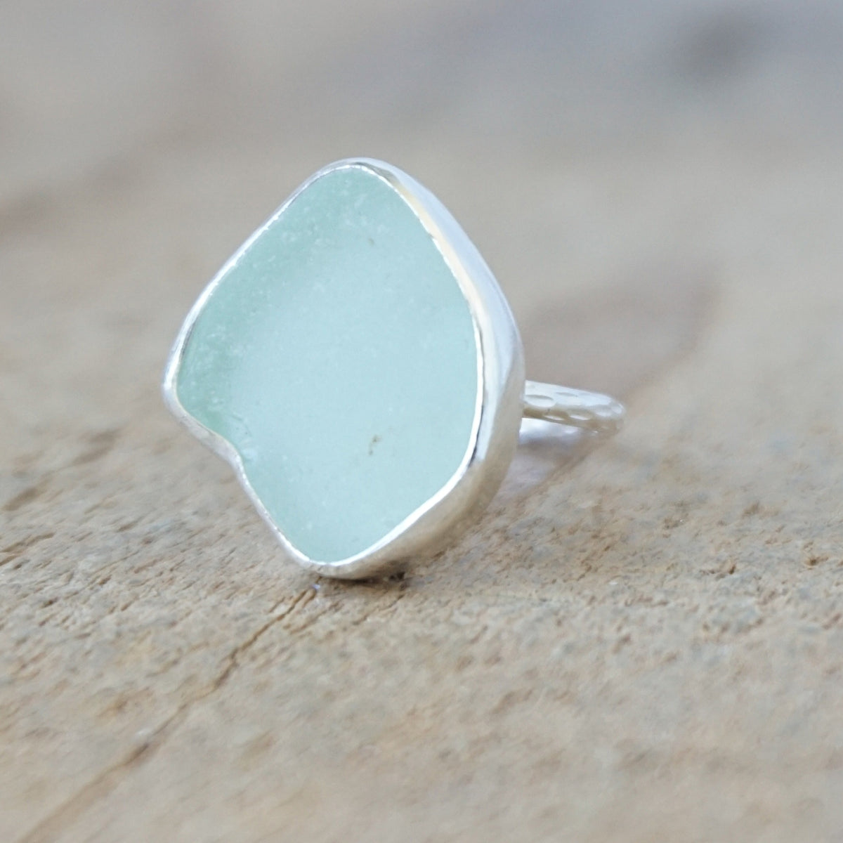 silver ring with a piece of seafoam green sea glass, against a wooden background