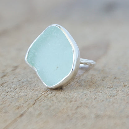 silver ring with a piece of seafoam green sea glass, against a wooden background