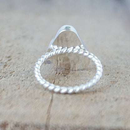 back view of a silver ring with a piece of seafoam green sea glass, against a wooden background