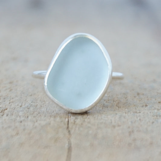 silver ring with a piece of light blue sea glass, against a wooden background