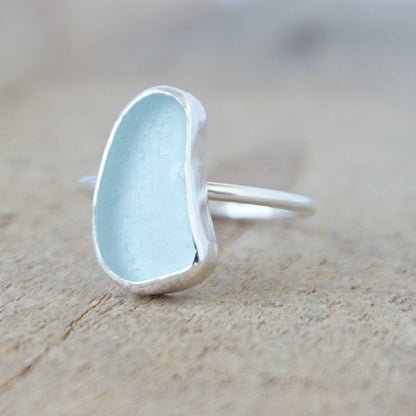 silver ring with a piece of light blue sea glass, against a wooden background