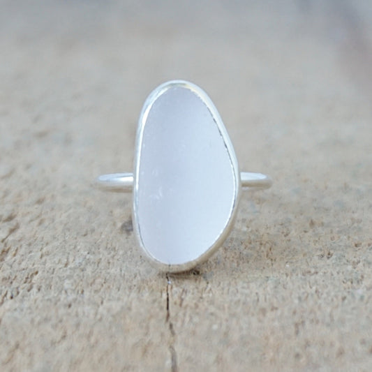 silver ring with a piece of pale lavender sea glass, against a wooden background