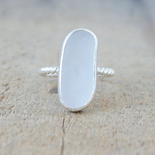 silver ring with a piece of pale lavender sea glass, against a wooden background