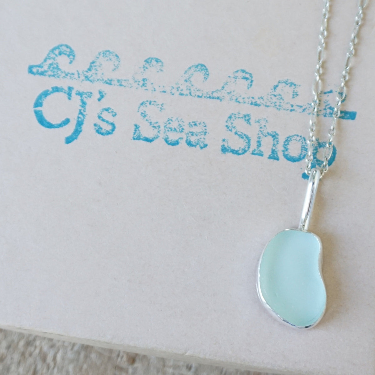 silver pendant with seafoam green sea glass, displayed on a gift box
