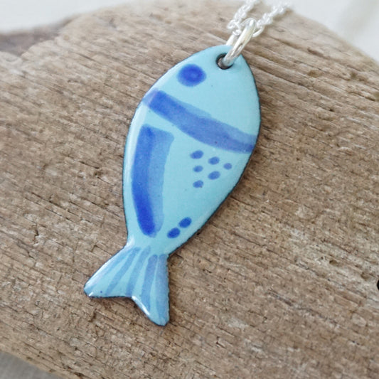 blue enamel fish shaped pendant, against a wooden background