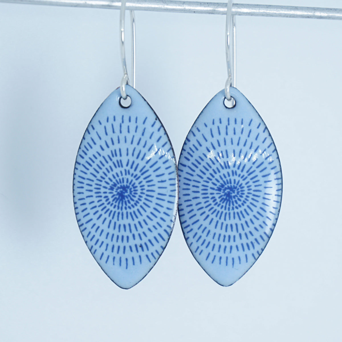 a pair of light purple enamel marquis shaped earrings with blue accents, against a white background