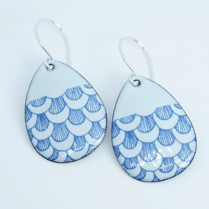 a pair of seafoam green enamel teardrop shaped earrings with blue fish scale accents, against a white background