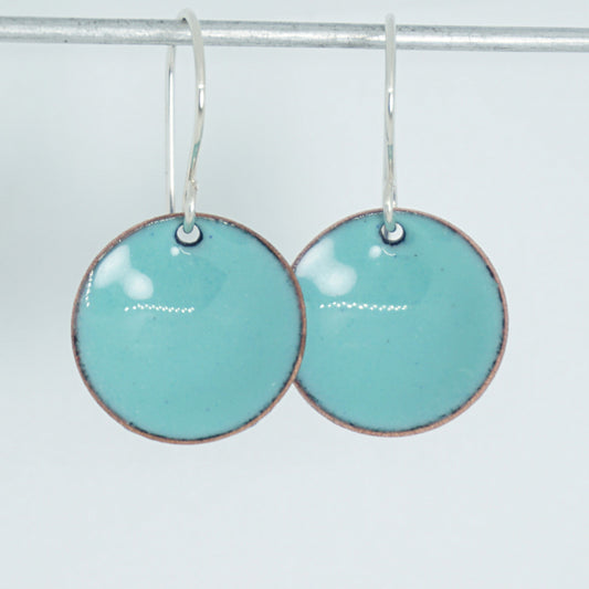 A pair of round green enamel earrings against a white background
