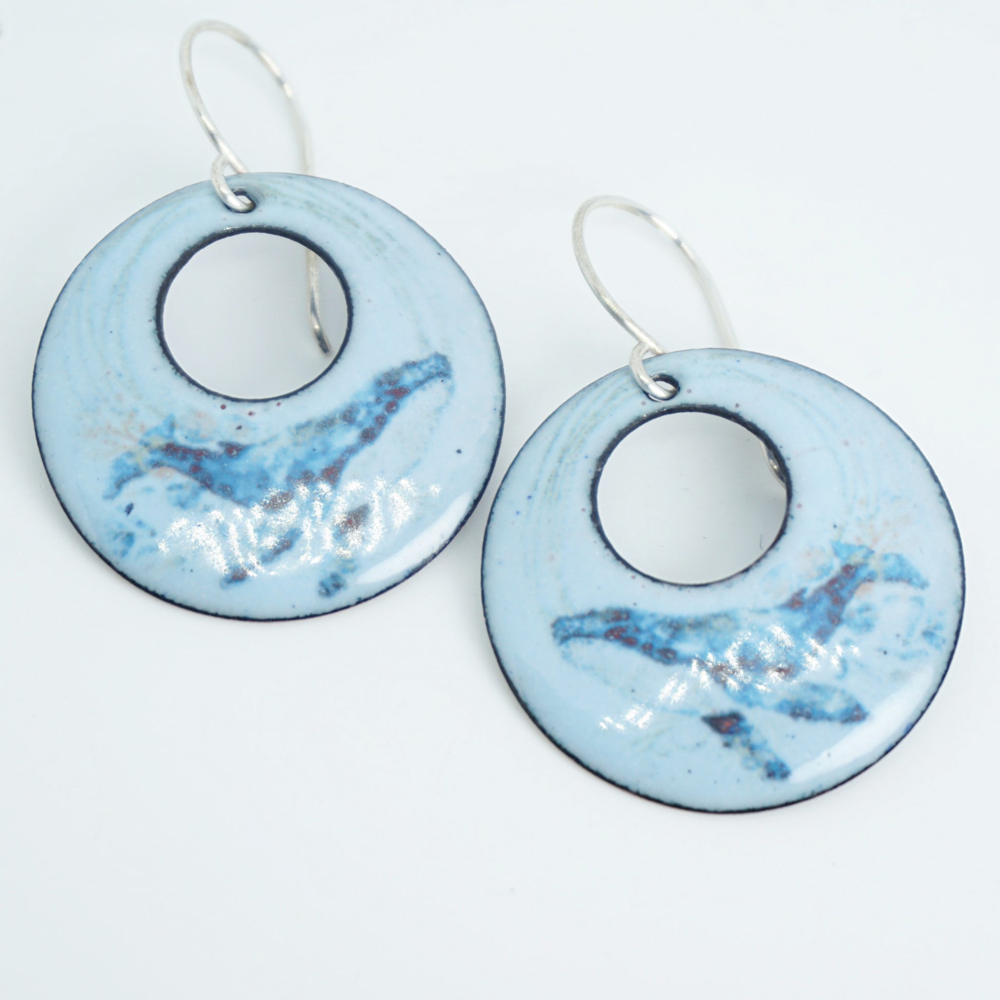 Pair of blue enamel earrings with a Whale design on white background
