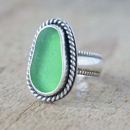 green sea glass ring with a decorative trim on a wooden background
