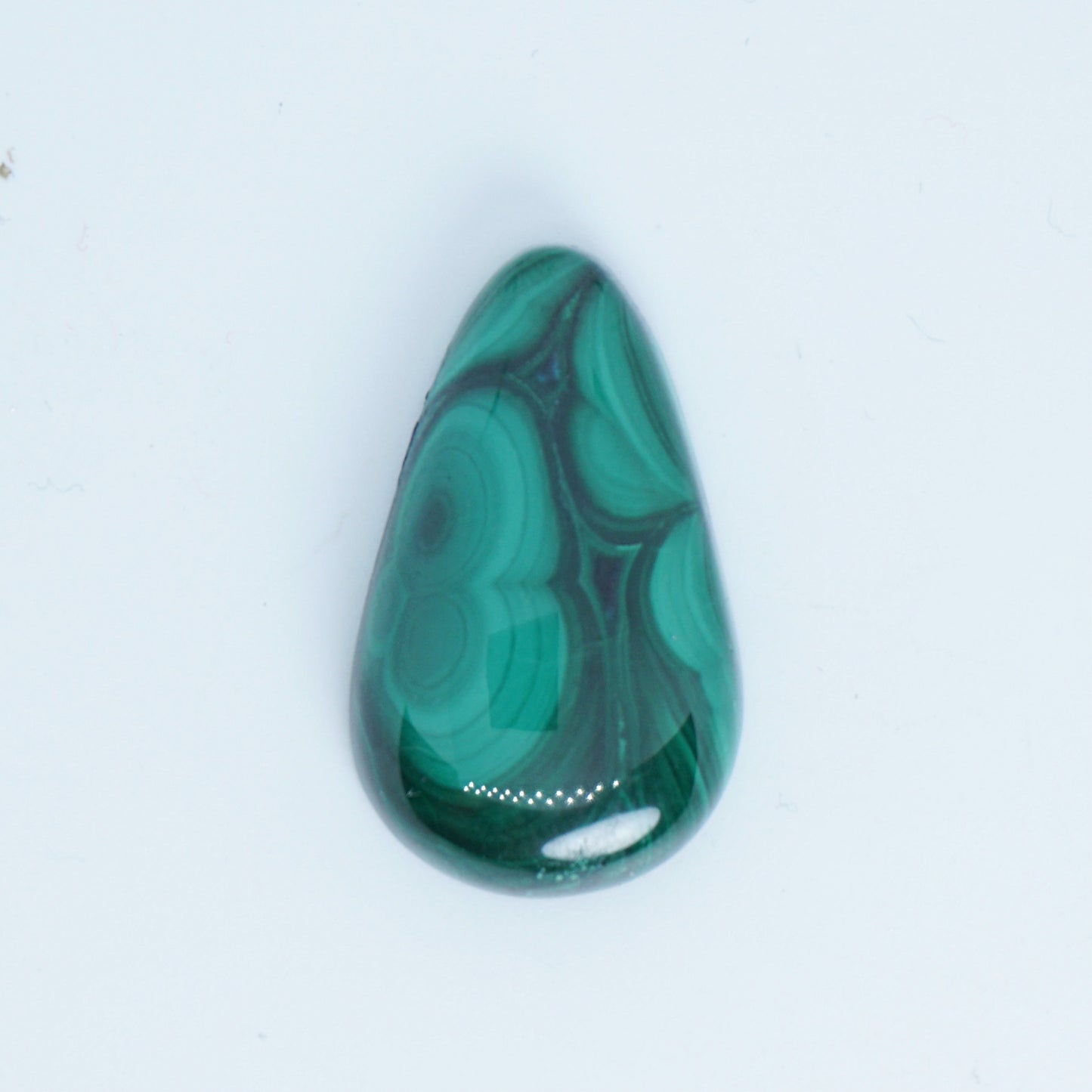 Teardrop-shaped malachite stone on a white background