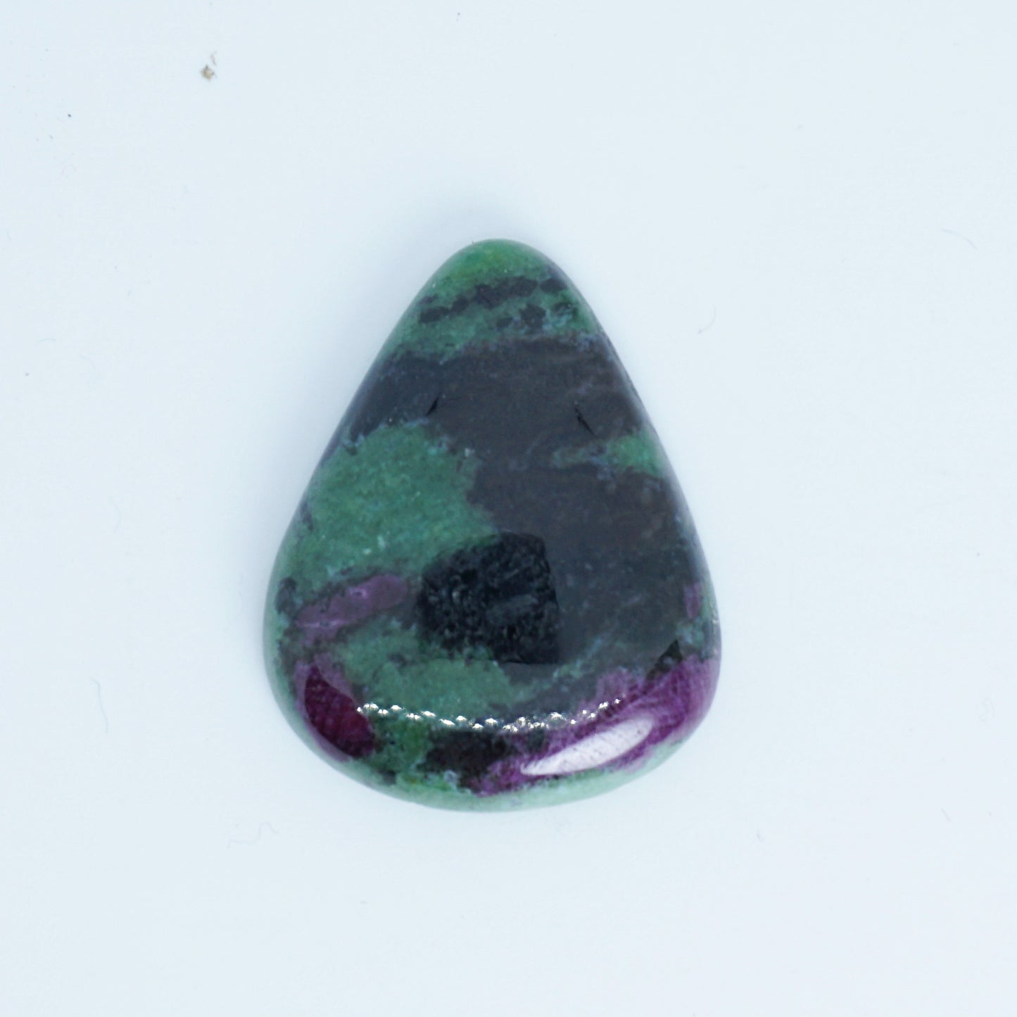 Teardrop-shaped gemstone with green, purple, and black colors on a white background
