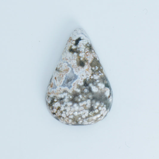 Teardrop-shaped ocean jasper stone with a textured surface on a light gray background