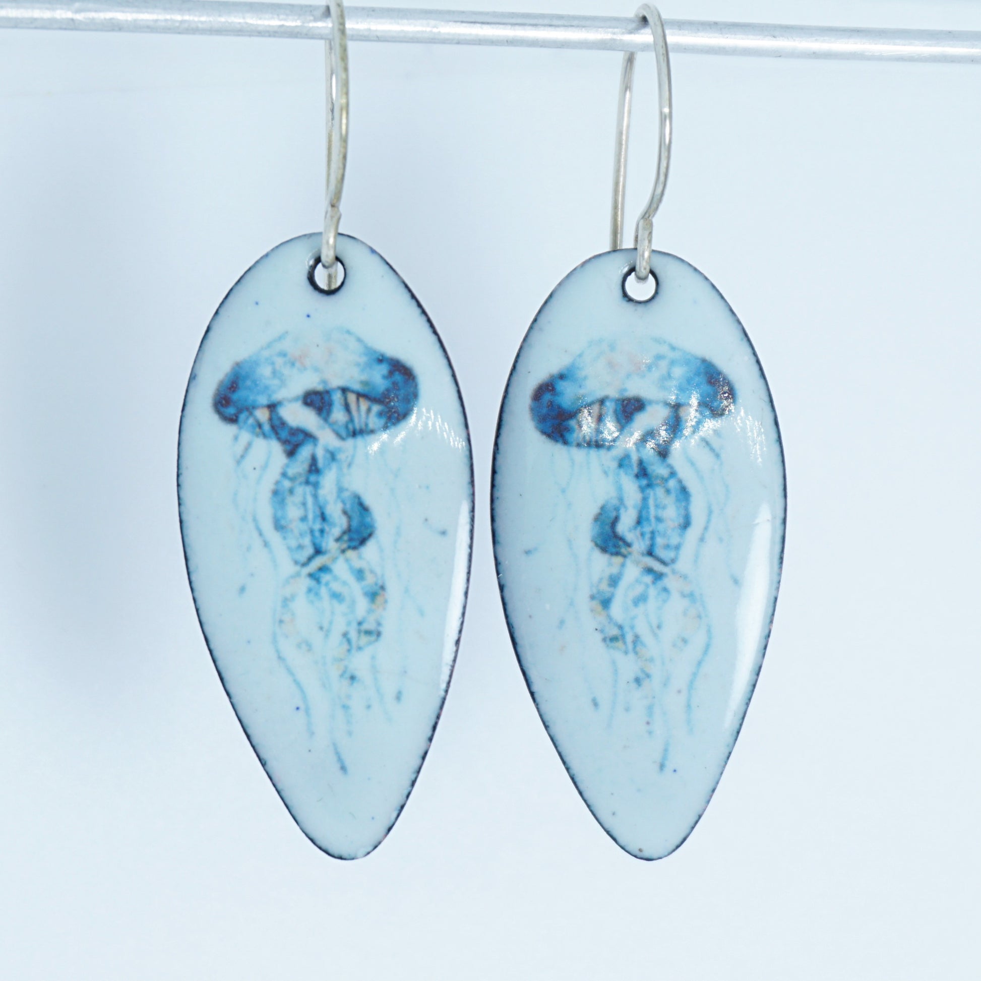 teardrop shaped earrings with jellyfish design on a white background