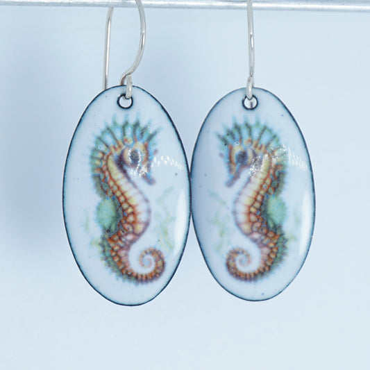 oval shaped earrings with seahorse design on a white background