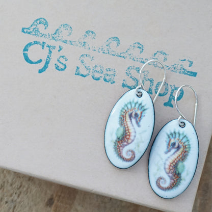 Oval earrings with seahorse design on a gift box