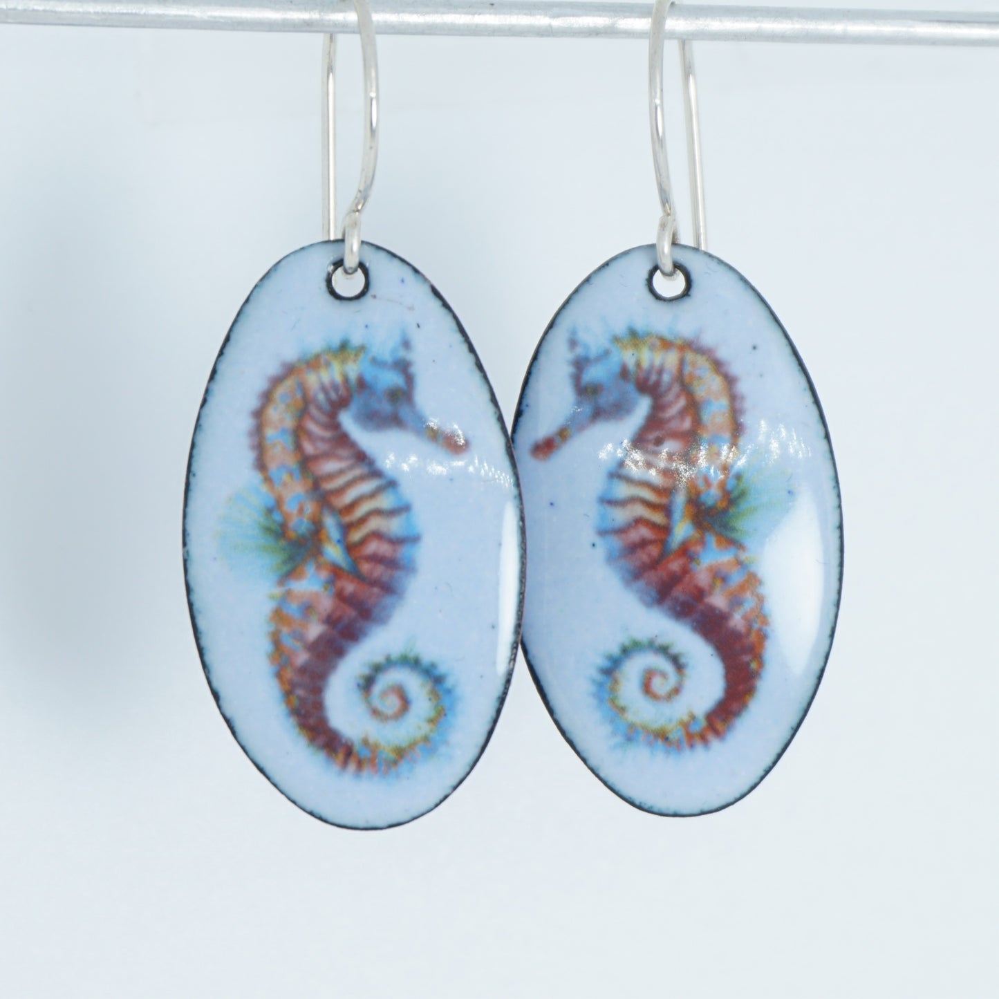 Pair of earrings with seahorse designs on a white background