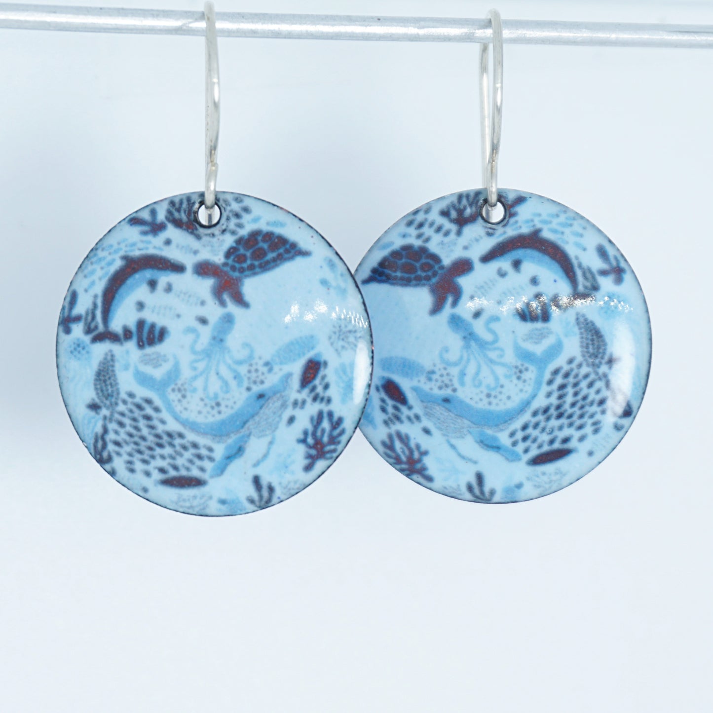 light blue circular earrings with sea life motif on a white background