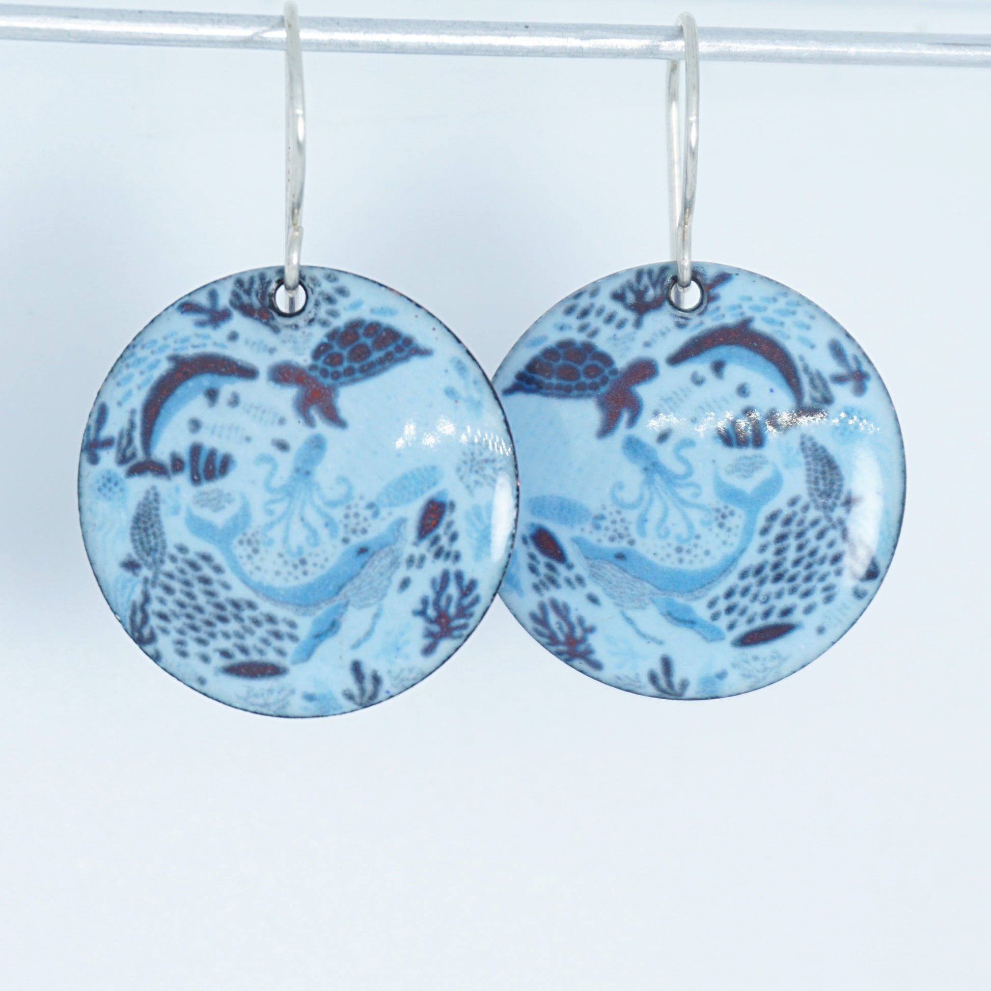 light blue circular earrings with sea life motif on a white background