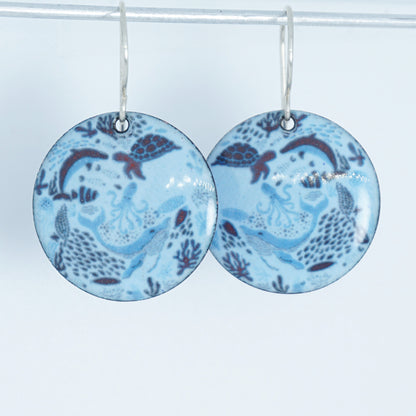 light blue circular earrings with sea life motif on a white background