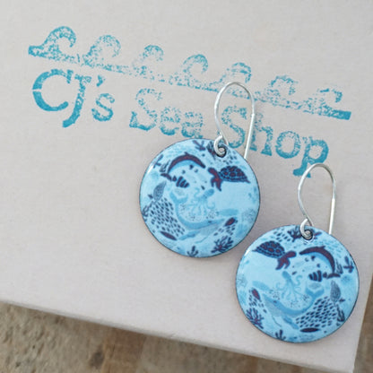 Blue enamel earrings with sea-themed design on a gift card