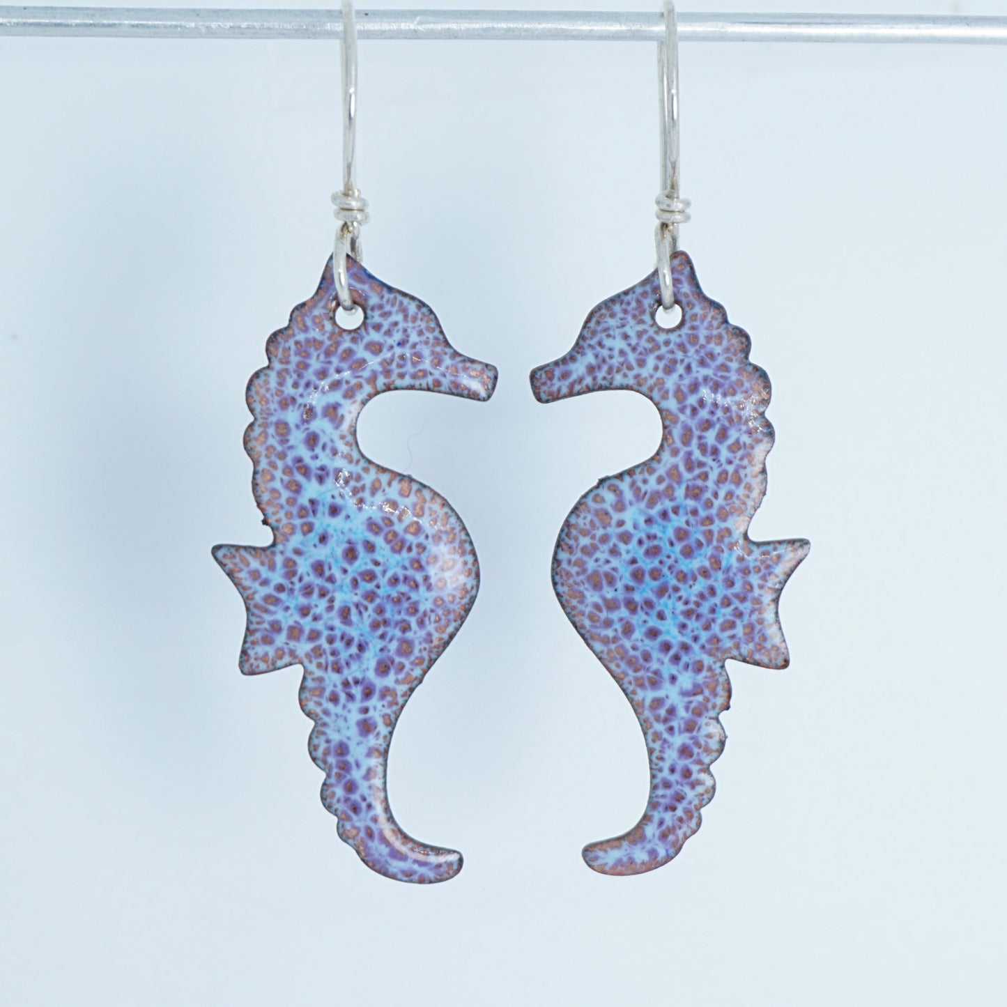 Pair of seahorse-shaped earrings with a speckled pattern on a white background