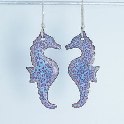 Pair of seahorse-shaped earrings with a speckled pattern on a white background