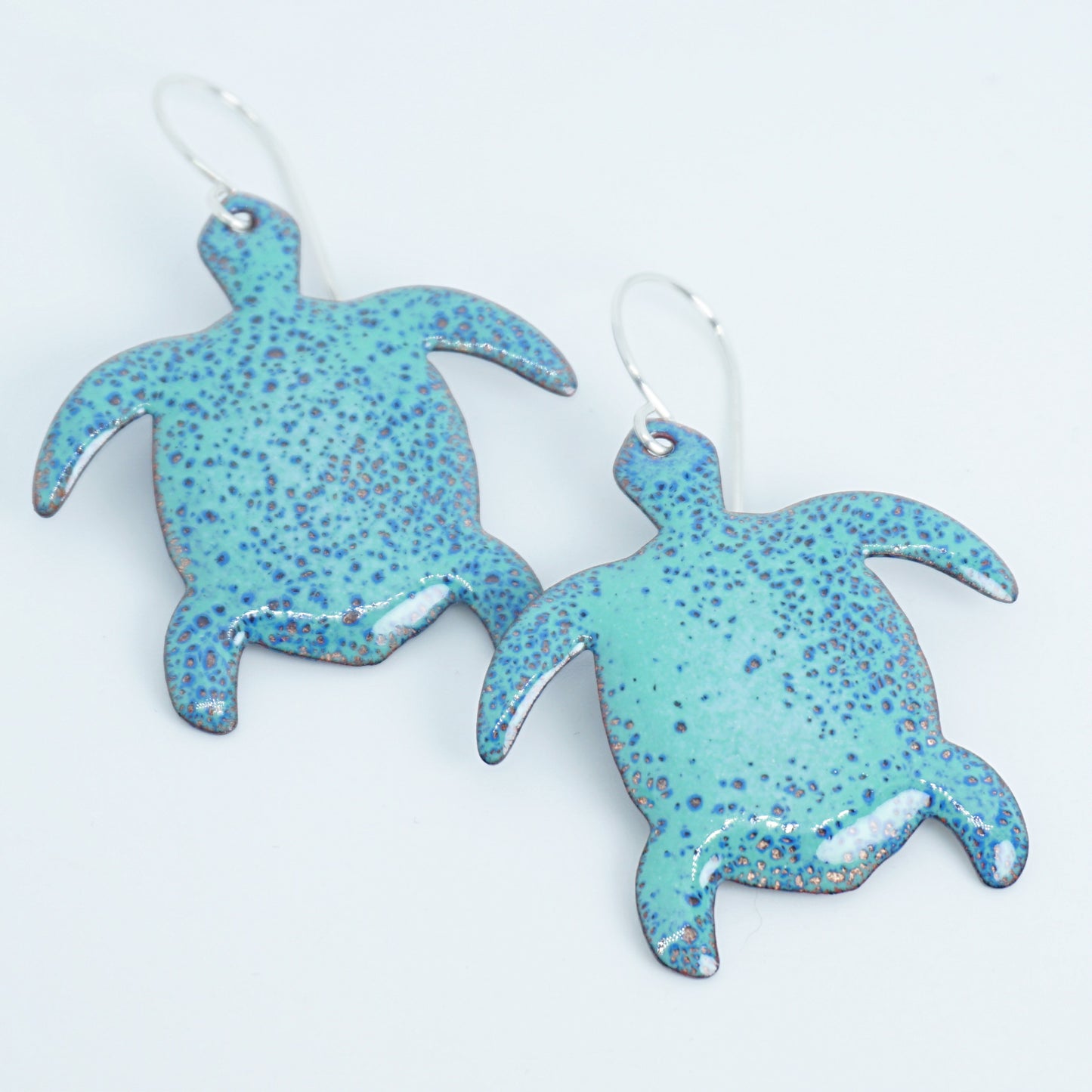 Green speckled turtle-shaped earrings on a white background